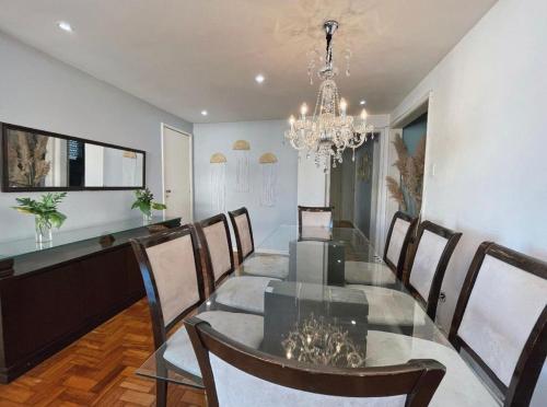 a dining room with a glass table and a chandelier at Apartamento c/vista p o mar no Leme in Rio de Janeiro