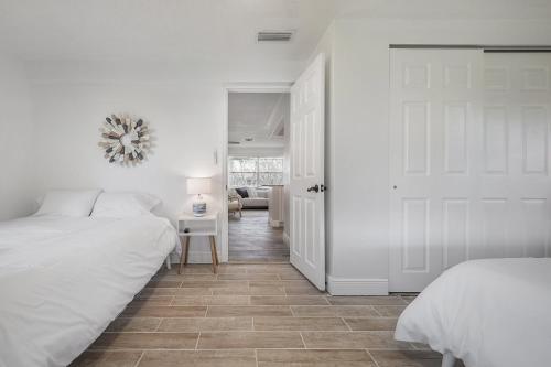 a white bedroom with two beds and a door at Upgraded Seminole home in a quiet neighborhood in Seminole