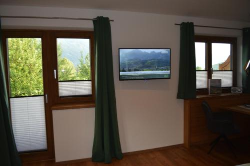 a room with windows with green curtains and a flat screen tv at Ramseiderhof in Saalfelden am Steinernen Meer