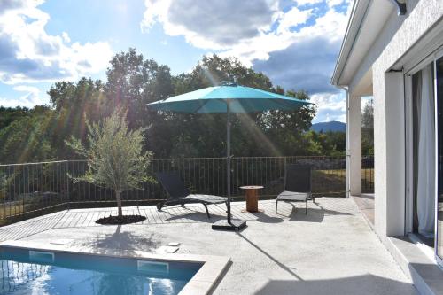 a patio with two chairs and an umbrella next to a pool at Gîtes des Clapas Lisa, villa**** piscine privée in Balazuc