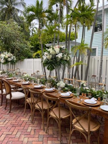 einen langen Holztisch mit Stühlen und Blumen auf einer Terrasse in der Unterkunft The Porch on Frances Inn - Adults Exclusive in Key West