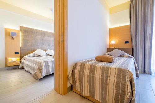 a hotel room with two beds and a mirror at Hotel Mare in Lignano Sabbiadoro