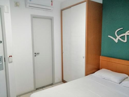 a bedroom with a white bed and a green wall at Bristol Praia do Canto Apart Hotel in Vitória