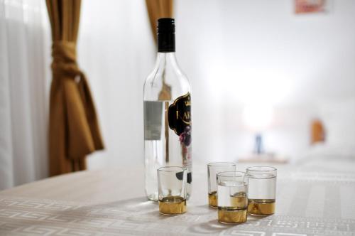 a bottle of wine and three glasses on a table at Stil Park Apartmani in Vrnjačka Banja