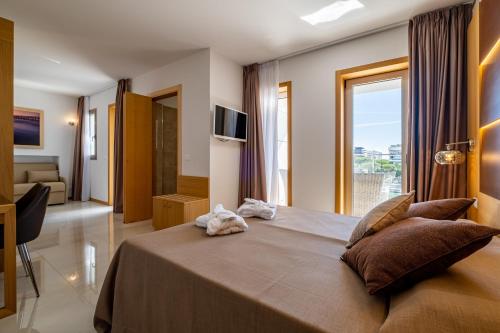 una camera da letto con un grande letto con una grande finestra di Hotel Mare a Lignano Sabbiadoro