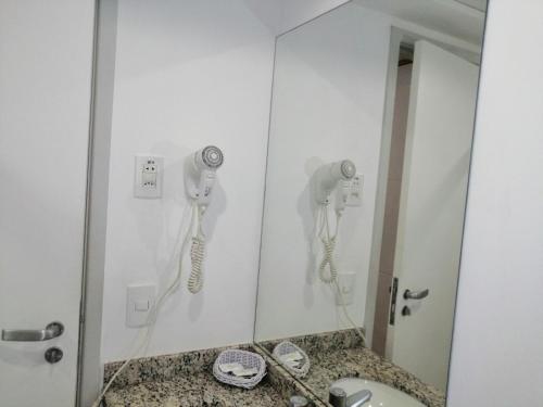 a bathroom with a mirror and a phone on the wall at Condomínio Bristol Praia do Canto Apart Hotel in Vitória