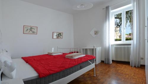 a bedroom with a bed with a red blanket and a window at Casa Marisa in Gargnano