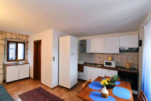 a kitchen with white cabinets and a table in a room at Freya's Apartments Medulin in Medulin