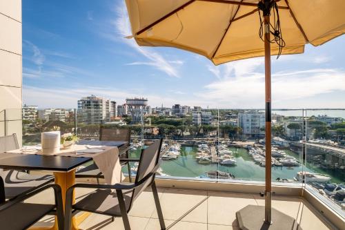 a balcony with a table and an umbrella and a harbor at Hotel Mare in Lignano Sabbiadoro