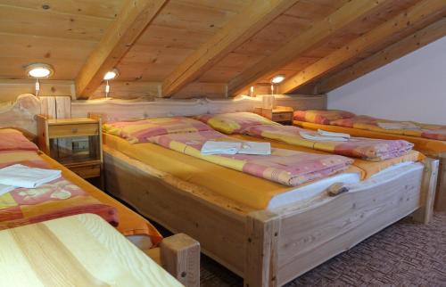 a group of beds in a room with wooden ceilings at Ranč Podlesok in Hrabušice