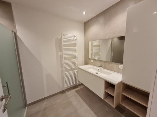 a white bathroom with a sink and a mirror at Vakantiehuis Mariakerke in Ostend