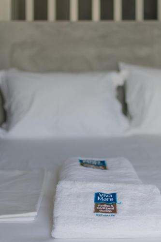 a bed with white sheets and a blue sign on it at Viva Mare Studios in Astypalaia Town