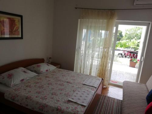 a bedroom with a bed and a window with a patio at Apartments Medici in Zaostrog