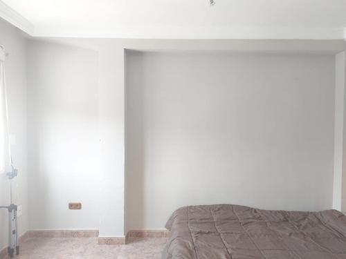 - une chambre avec un lit et un mur blanc dans l'établissement Apartamento Nieves, à Torrox