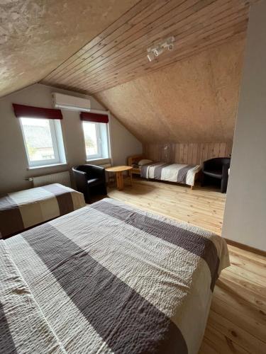 a bedroom with two beds and a wooden ceiling at Pulkvedis Guest House in Ventspils