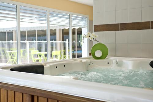 a bath tub with a vase of flowers in it at Vacancéole - Domaine du Green in Rivières