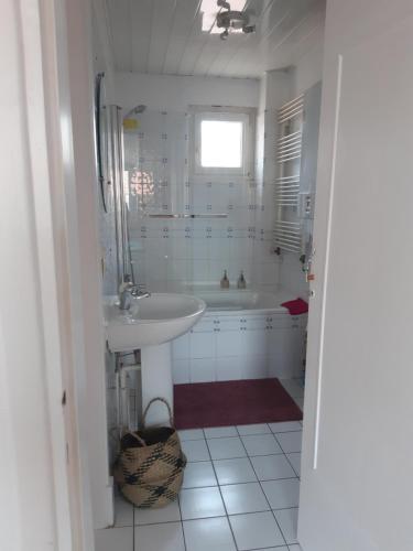 een witte badkamer met een wastafel en een bad bij Appartement Malo les Bains à deux pas de la plage in Duinkerke