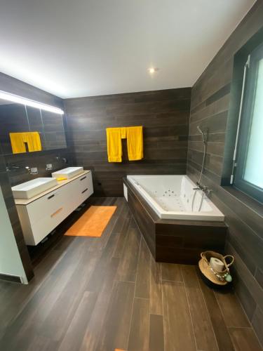 a bathroom with a large tub and a sink and a tub at Villa luxueuse à 10 minutes de Crans-Montana in Crans-Montana