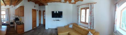 sala de estar con sofá y TV en la pared en Vica Apartman, en Balatonberény