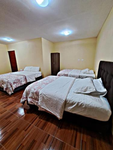 two beds in a hotel room with wooden floors at La Ruta in Paracas