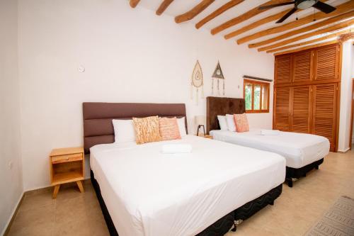 two beds in a room with white sheets at Casa Nino Holbox Villa in Holbox Island
