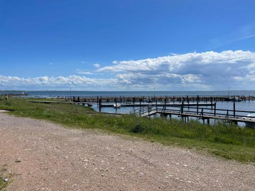 a pier in the water next to a dirt road at Pia’s Country House in Båstad