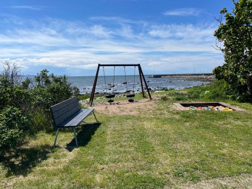 a park bench sitting in the grass next to a swing at Pia’s Country House in Båstad