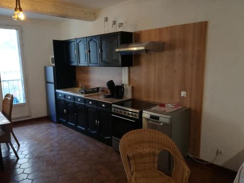 uma cozinha com armários pretos e um fogão em Agréable maison de ville rénovée em Villeneuve-lès-Maguelonne