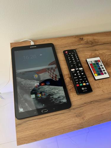 a tablet and a remote control sitting on a table at Poolhouse Flip Flop - mit privatem Pool in Vir