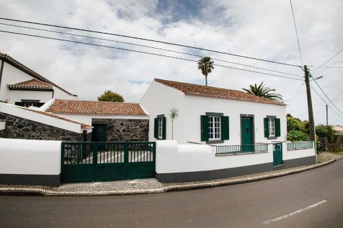 a white house with green doors on a street at Casa das Palmeiras in São Vicente Ferreira