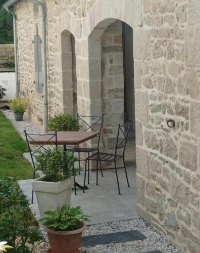 a patio with a table and chairs in a stone building at La Sabotiere in Plumeliau Bieuzy