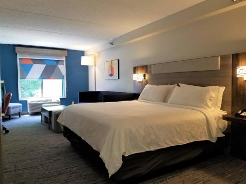 a hotel room with a large bed and a living room at Holiday Inn Express Apex - Raleigh by IHG in Apex