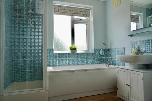 a bathroom with a tub and a sink and a window at JDB Chesterfield 3 Bedroom House in Whitton