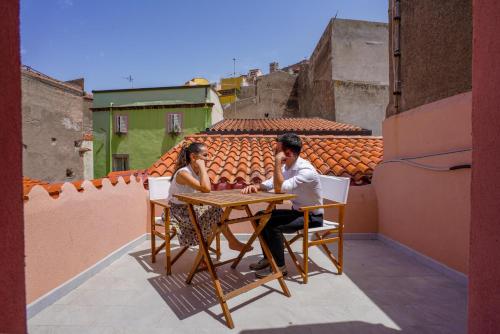 a man and woman sitting at a table on a balcony at Casa Mirto in Bosa