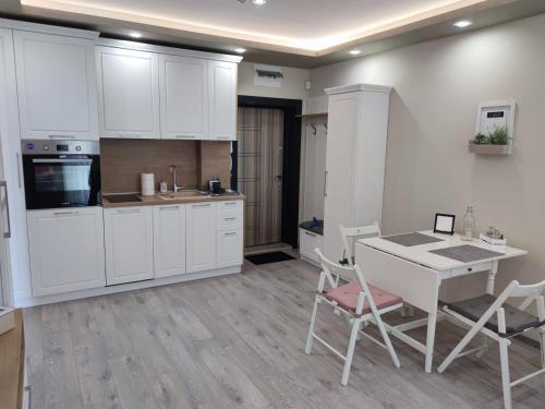 ドブリチにあるFlowers Apartmentの白いキャビネット、テーブルと椅子付きのキッチンが備わります。