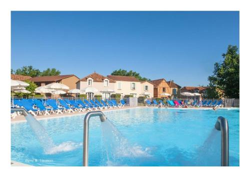 une grande piscine avec des chaises bleues et des personnes dans l'établissement Charmant Appartement avec piscine., à Monflanquin