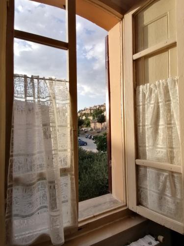 a window with curtains and a view of a street at La Musa di Spello in Spello