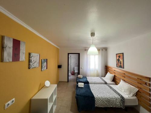 1 dormitorio con 2 camas y pared amarilla en Surf House Helena, en Baleal