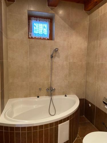 a bath tub in a bathroom with a window at Centrum Vendégház in Tihany