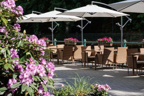 a group of tables and chairs with umbrellas and flowers at Villa Basileia Riverside in Karlovy Vary