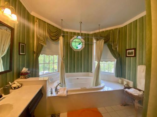 baño con cortinas verdes y bañera con ventana en The Cypress Inn, en Conway