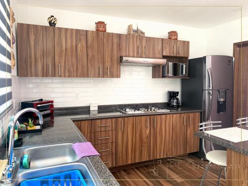 a kitchen with wooden cabinets and a stainless steel refrigerator at Departamento Loma-Bonita in Guadalajara