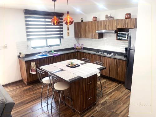 a kitchen with wooden cabinets and a island with bar stools at Departamento Loma-Bonita in Guadalajara