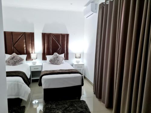 a hotel room with two beds and curtains at Oyster Guest House in Durban