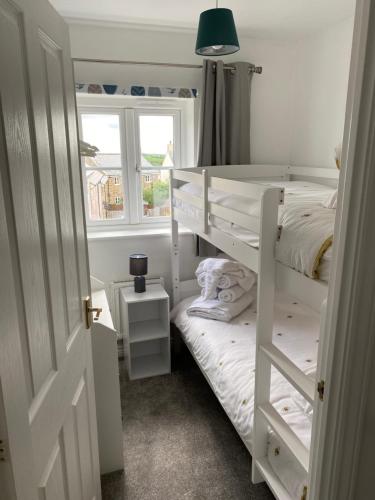 a bedroom with two bunk beds and a window at Stylish 3 bed home with allocated parking for 2 in Liskeard