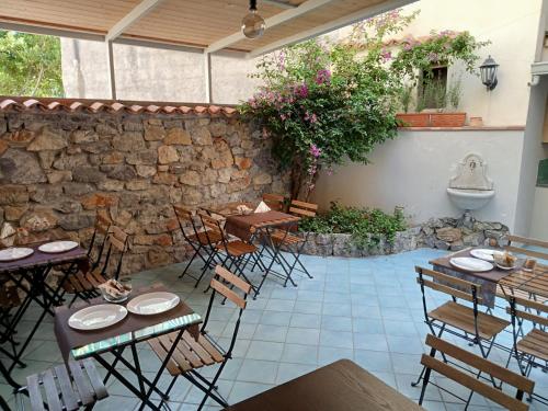 a patio with tables and chairs and a stone wall at Borgo 800 in San Nicola Arcella