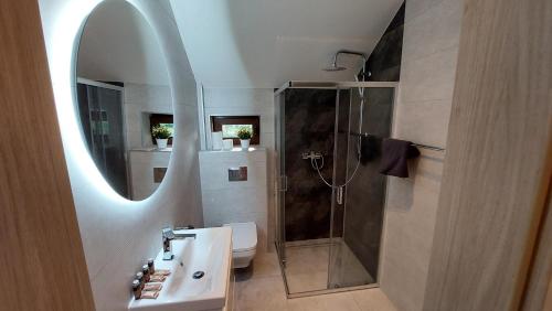 a bathroom with a sink and a shower with a mirror at Apartamenty Starowiejska 39, Ryczów - 10km od Zator Energylandia in Zator