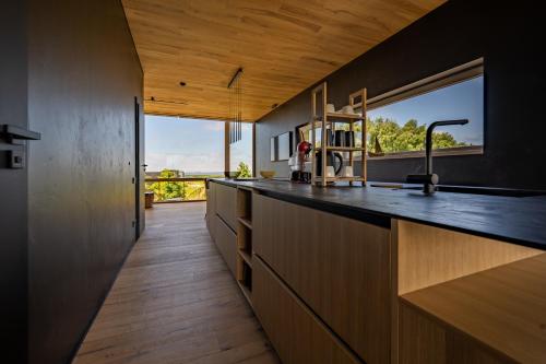 a kitchen with a counter with a sink and a window at Jaukūs ART stiliaus apartamentai antrame aukšte su vaizdu į marias in Svenele