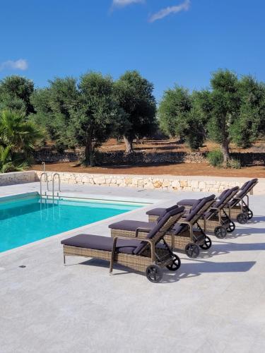 a row of lounge chairs next to a swimming pool at Villa Dolce Far Niente Ostuni in Ostuni