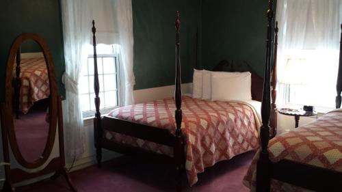 a bedroom with two four poster beds and a mirror at The Country Inn of Berkeley Springs in Berkeley Springs